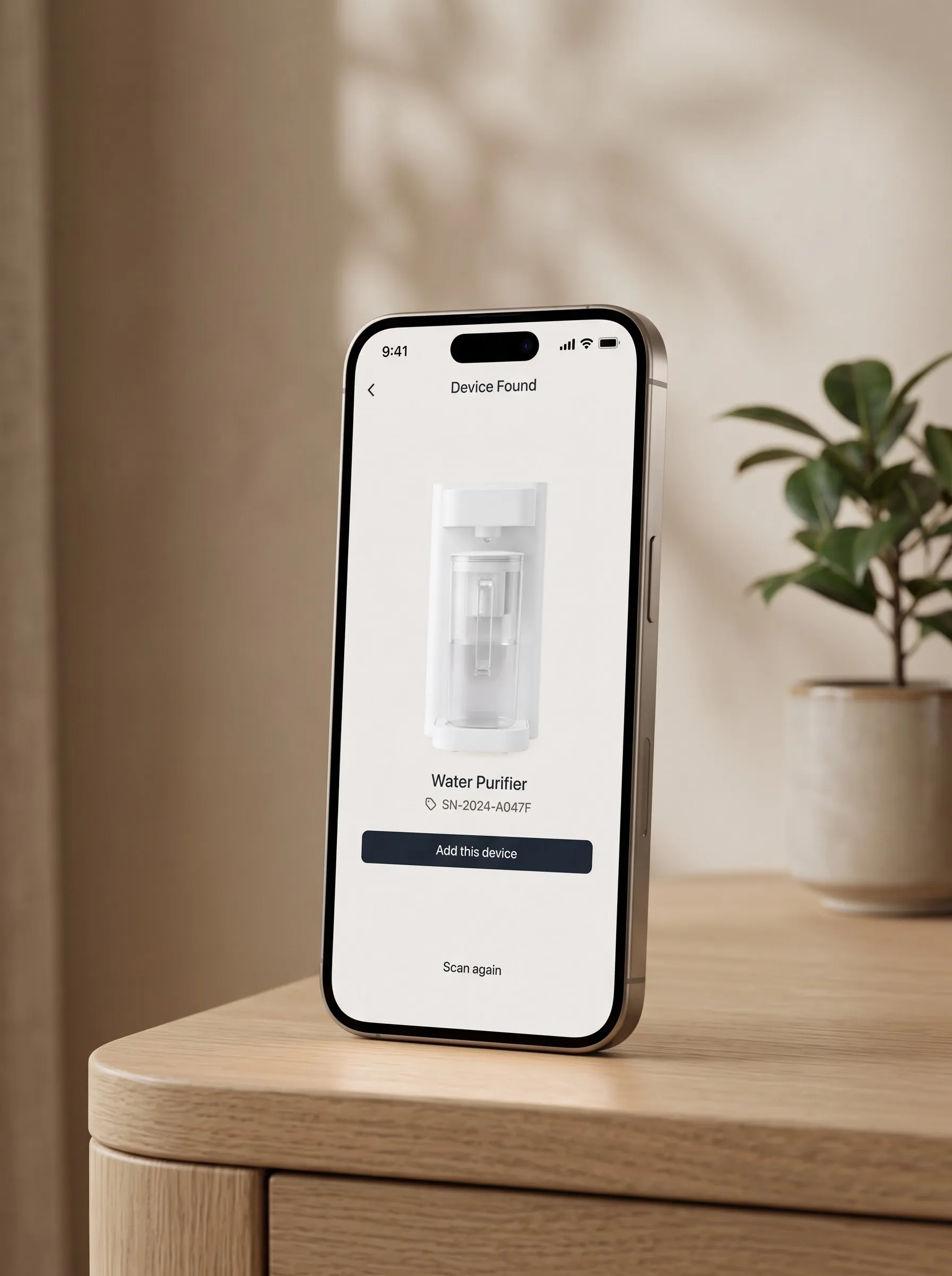 A phone on a side table showing a screen headed Device Found, with a water purifier pictured above its name and serial number, a button reading Add this device, and Scan again underneath.